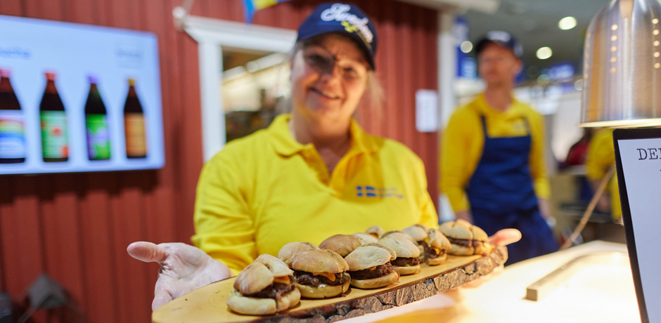 Kvinna i Sverigetröja serverar älgfärsburgare