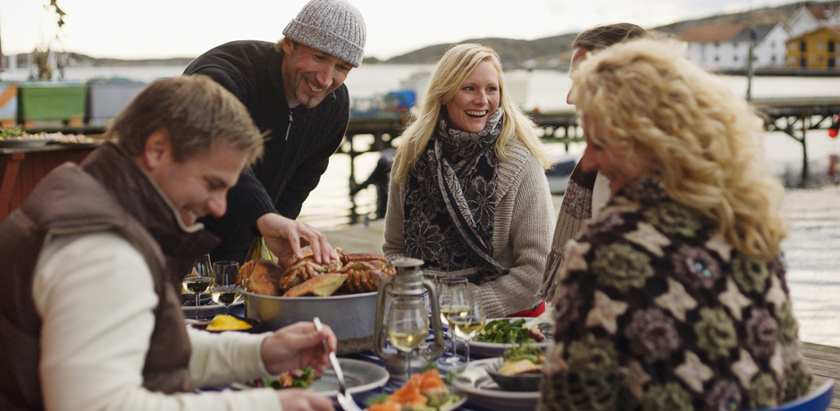 Människor som sitter på en brygga och äter tillsammans.